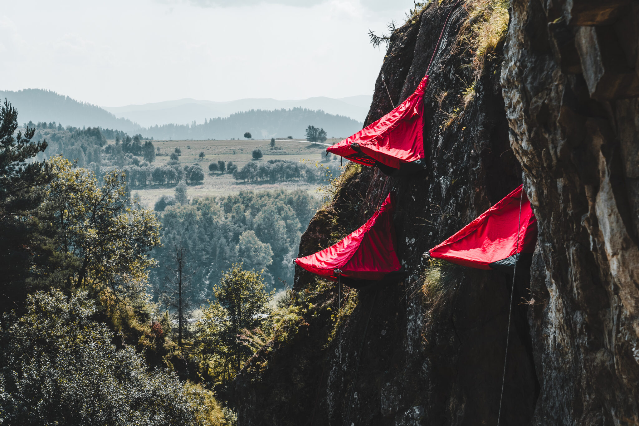 Czerwone namioty wiszące na skałach