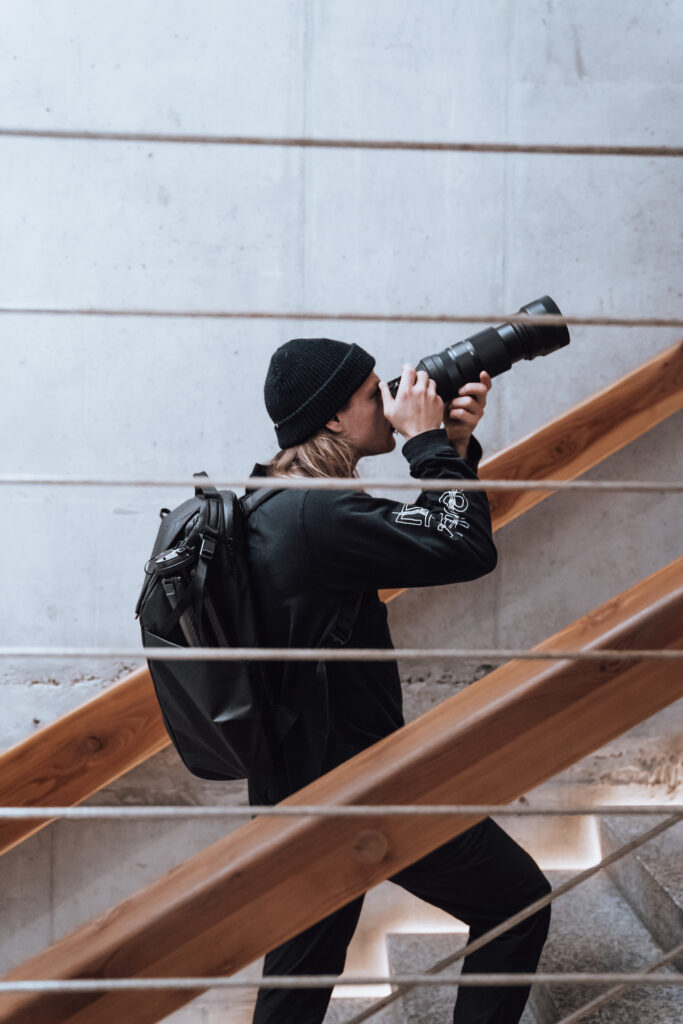 Fotograf Paweł Zalejski robi zdjęcie aparatem z dużym obiektywem i wchodzi po schodach