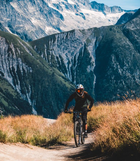 Paweł Zalejski jadący w kasku na rowerze a w tle góry Alpy
